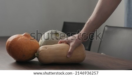 man put pumpkins on walnut table, wide photo
