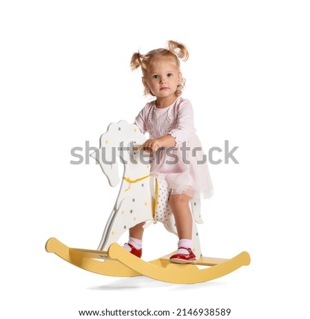 Adorable baby girl with rocking horse on white background Royalty-Free Stock Photo #2146938589