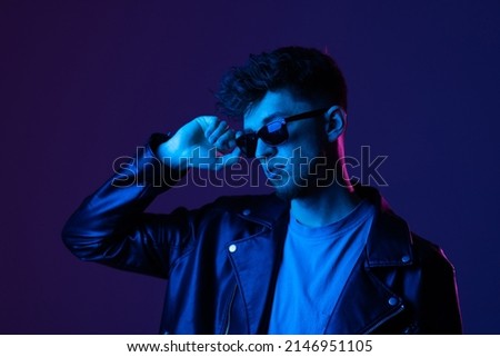 Portrait of attractive guy wearing specs looking far away isolated over dark neon purple color background