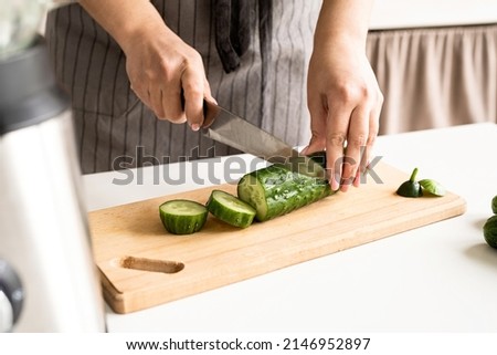 Healthy eating, dieting concept. High angle view of female hands cutting cucumber in the kitchen Royalty-Free Stock Photo #2146952897