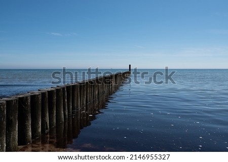 maritime background, wooden breakwater in calm baltic sea against blue sky