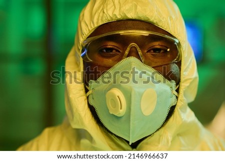 Face of African American male virologist in protective coveralls, eyeglasses and respirator standing in front of camera in laboratory Royalty-Free Stock Photo #2146966637