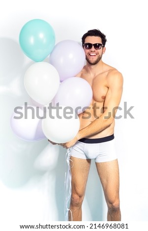 Handsome Caucasian Man Impressed Something Positive While on Party Or Club Presentation Wearing Contrasty Underware Outfit Holding Colorful Airballoons. Vertical Image