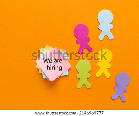 We are hiring text on sticky notes  with colorful paper people  on orange  background 