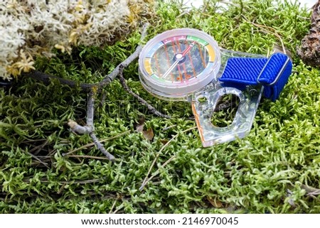 Compass for orienteering lies on the green grass side view