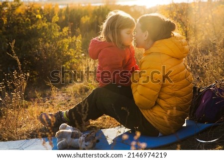 family spends time together in nature. happy family Mom and the little daughter hug and play in autumn outdoor at sunset. 