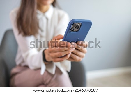 Businesswoman with mobile phone in hand. Asian business woman texting on her cell phone at the office and looking happy - communications concepts