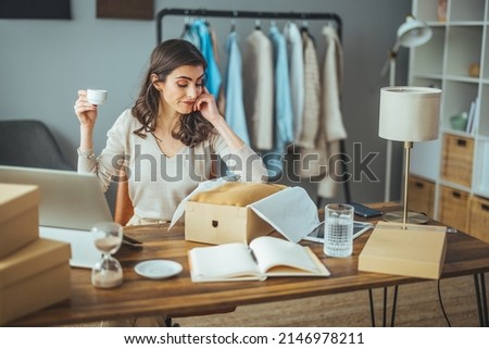 Young beautiful happy business woman owner of SME online using laptop receive order from customer with parcel box packaging at her startup home office, online business seller and delivery


