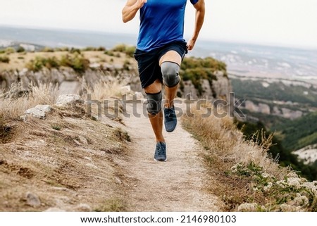 male runner running trail in knee pads Royalty-Free Stock Photo #2146980103