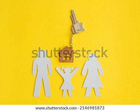 Silhouette of a white paper family, a little girl pulls her hands up to the keys with a wooden keychain house. The concept of mortgage lending for the purchase of new housing. Place for text.