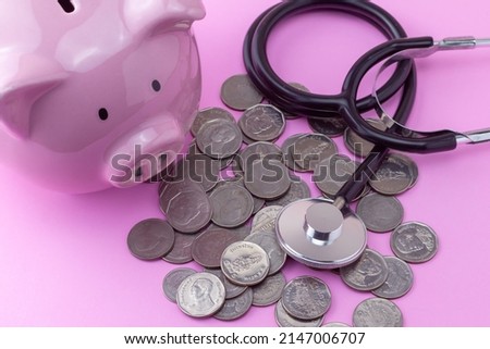 pink piggy bank Stack of coins and stethoscope placed on pink background. Finance and medical care concept.