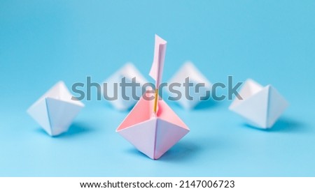 Leadership concept. Pink paper ship with flag lead among paper ship white. One leadership leads other ships.