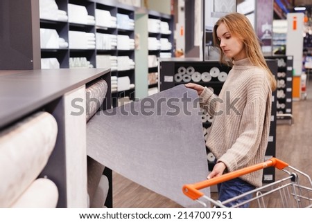 Young woman choose wallpaper in hardware store. Home design and renovation concept