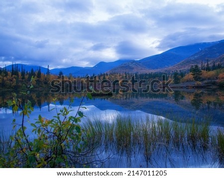 Reflection of mountains and clouds in the calm surface of the lake. Peaceful landscape. Khibiny. photo