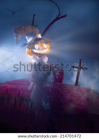 Scarecrow with head of pumpkin on the cemetery