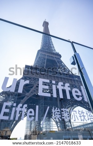 
view of the Eiffel Tower in Paris, France with the signage indicating access to the tower in the foreground. Blue sky in the background