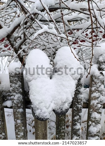 Galoshes, swept by snow. Hanging on the fence in winter