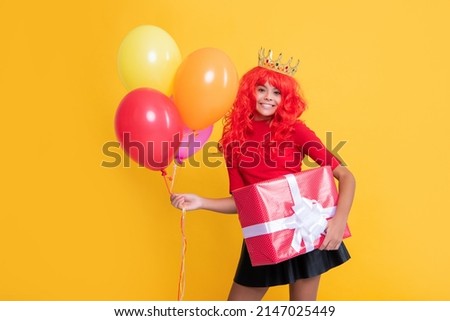 happy child in crown with present box and party balloon on yellow background