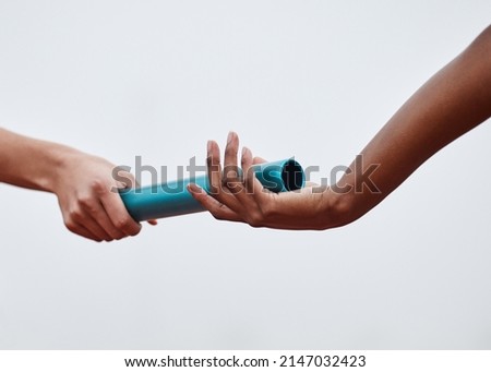 Nothing will stop us now. Shot of two athletes passing a baton during a relay race. Royalty-Free Stock Photo #2147032423