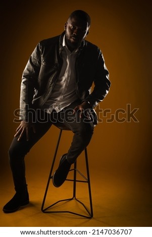 Casual dressed and hadnsome black male is posing on yellow background in studio