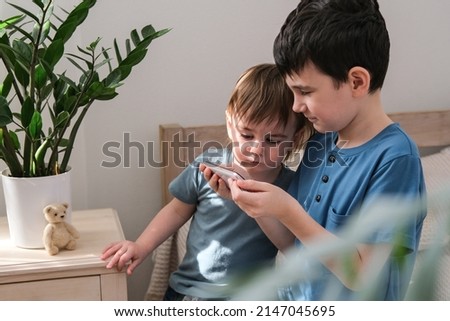 Two little brothers happily watching cartoons together on a smartphone. Children and gadget concept