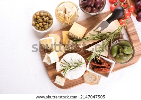 Charcuterie board with cheese slices and assortment of traditional Italian antipasti. Cheese platter on white table with copy space Royalty-Free Stock Photo #2147047505