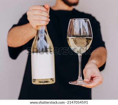 Man's hand holding glass and bottle of white wine