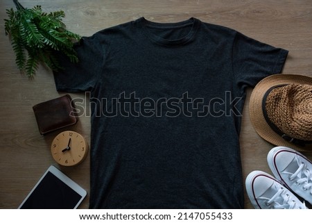 Mockup of a black t-shirt blank shirt template with accessories on the wooden table background, lifestyle and travel concept