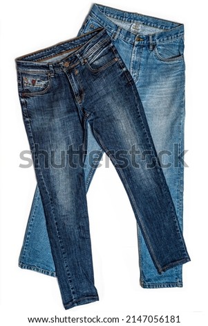 Various blue jeans pants or trousers made of blue-colored denim cloth. Closeup abstract texture cotton fabric for design. Pair of jeans, pockets, rivets, buttons, seams, white isolated background