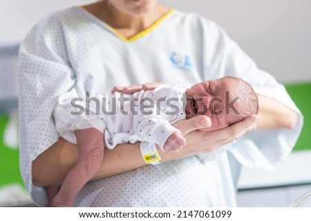 woman who has just given birth in the hospital holds her newborn baby in her arms face down to calm the crying colic of the infant. newborn care Royalty-Free Stock Photo #2147061099