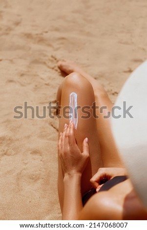 Closeup on female Hand applying solar  sun cream  on Leg. Skincare. Sun protection. Woman smear sunscreen moisturizing lotion on her smooth tanned legs. Girl Holding Sunblock. 