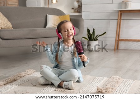 Cute little girl in headphones with hairbrush singing at home Royalty-Free Stock Photo #2147075719