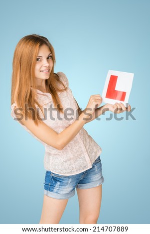 Young happy learner driver holding L-plate.
