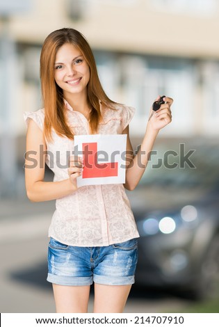 Young teenage learner driver holding L-plate and car keys.