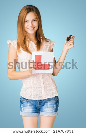 Young teenage learner driver holding L-plate and car keys.
