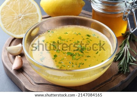 Bowl with lemon sauce and ingredients on table, closeup. Delicious salad dressing Royalty-Free Stock Photo #2147084165