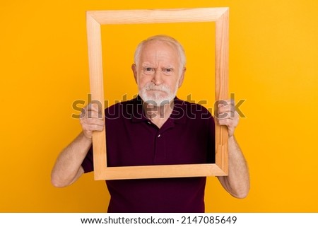 Photo of mature man hold wood frame moody frowning take album shots isolated over yellow color background