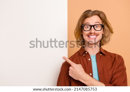 Portrait of handsome trendy cheerful smart red-haired guy showing ad copy place space isolated over beige pastel color background