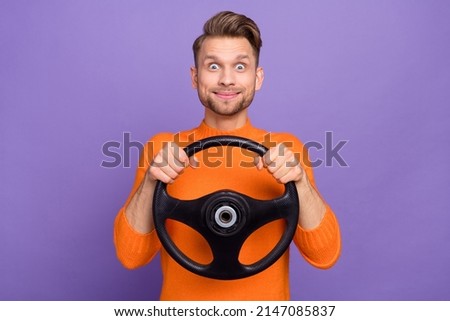 Photo of impressed funky guy dressed orange pullover scaring riding automobile isolated purple color background