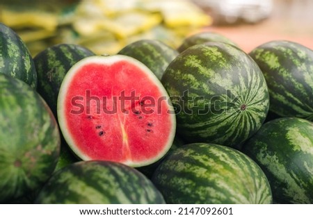 Several large sweet green watermelons and cut watermelons, several large sweet green watermelons are placed on a wooden table on a natural background for sale. Royalty-Free Stock Photo #2147092601