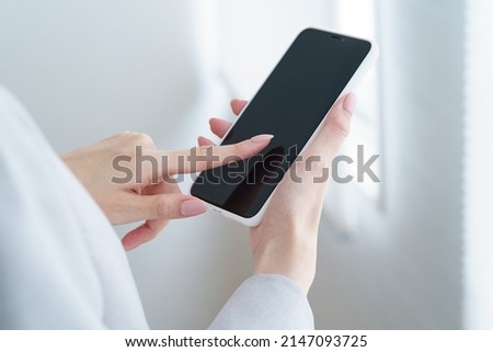 Woman holding a smartphone indoors Royalty-Free Stock Photo #2147093725