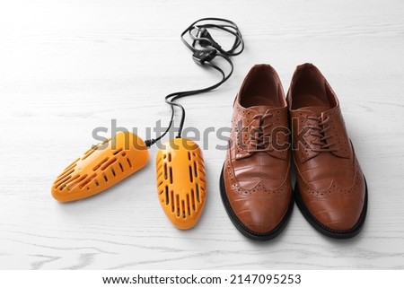 Shoes and electric dryer on white wooden background