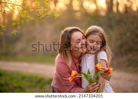 happy mothers day. child , daughter congratulates mother and gives a bouquet of flowers to tulips.