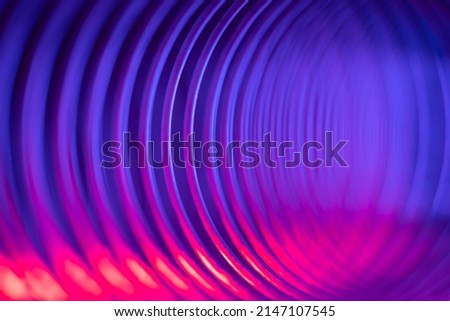 Closeup of coiled metal spring with sufficiently high strength and elastic properties in neon blue and pink light. Macro photo, selective soft focus. Abstract shot. Royalty-Free Stock Photo #2147107545
