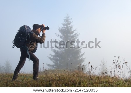 Photographer hiker taking picture of nature with digital camera
