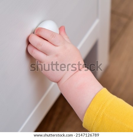 Danger for the baby to pinch the hand of the cabinet door or chest of drawers. Protect children from home furniture, kids safety Royalty-Free Stock Photo #2147126789