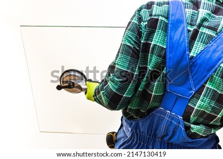 A glazier's worker holding a pane of thick glass in his hands with a special sucker 