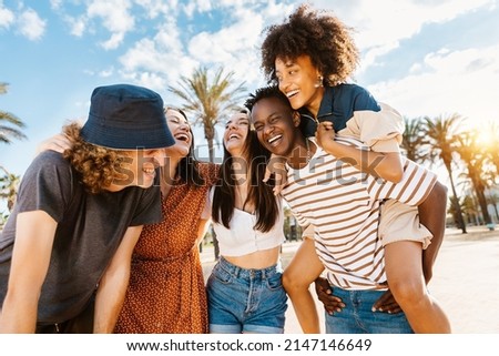 Group of multiracial happy young friends having fun together enjoying summer vacation on the beach - Focus on african couple
