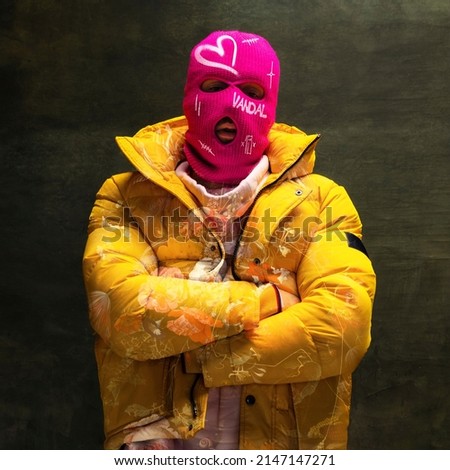 Contemporary art collage. Creative design. Stylish man in pink balaclava and yellow jacket isolated over textured dark green background. Modern style. Concept of street art, creativity, youth, fashion Royalty-Free Stock Photo #2147147271