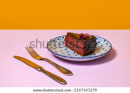 Dessert. Food pop art photography. Plate with cake on lilac color tablecloth over orange background. Retro 80s, 70s style. Complementary colors, Copy space for ad, text. Poster for sale